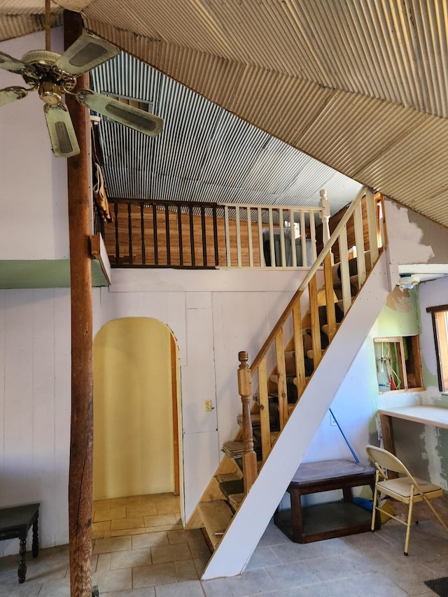 stairs featuring ceiling fan and wood walls