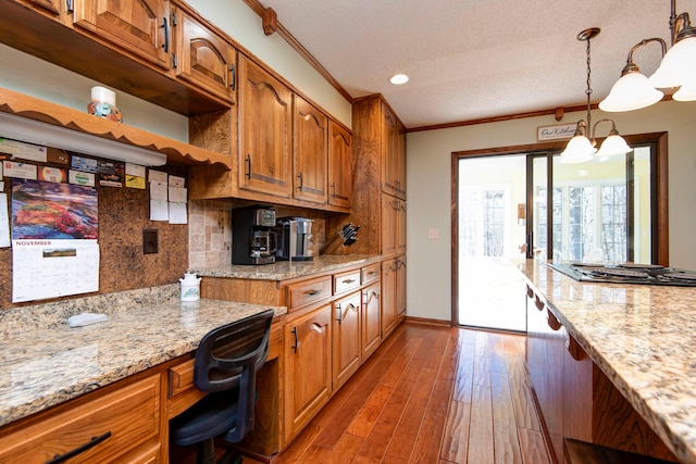 kitchen with hardwood / wood-style floors, pendant lighting, crown molding, a textured ceiling, and a notable chandelier