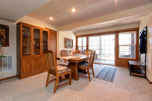 dining area featuring a textured ceiling and light carpet