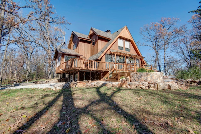 rear view of house featuring a wooden deck and a lawn