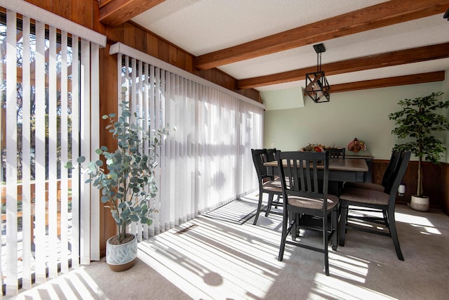 dining area featuring light carpet, beamed ceiling, and an inviting chandelier