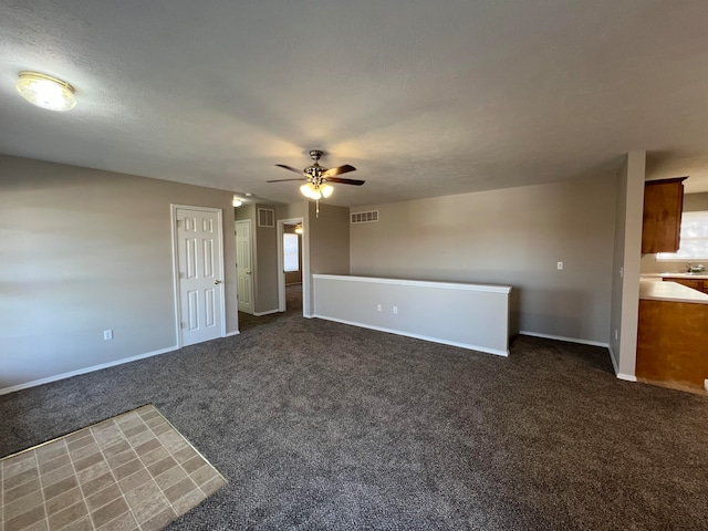 interior space featuring ceiling fan, a textured ceiling, and dark colored carpet