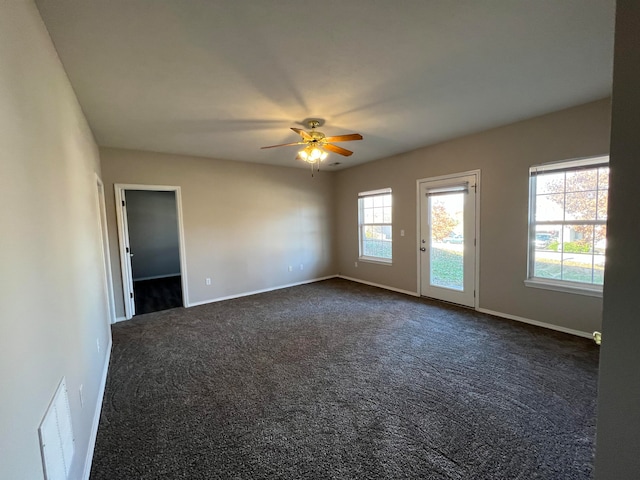 spare room with dark colored carpet and ceiling fan