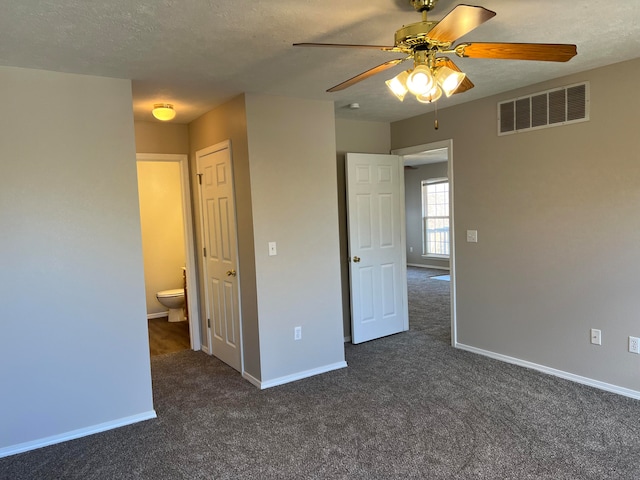 unfurnished bedroom featuring connected bathroom, ceiling fan, dark carpet, and a textured ceiling