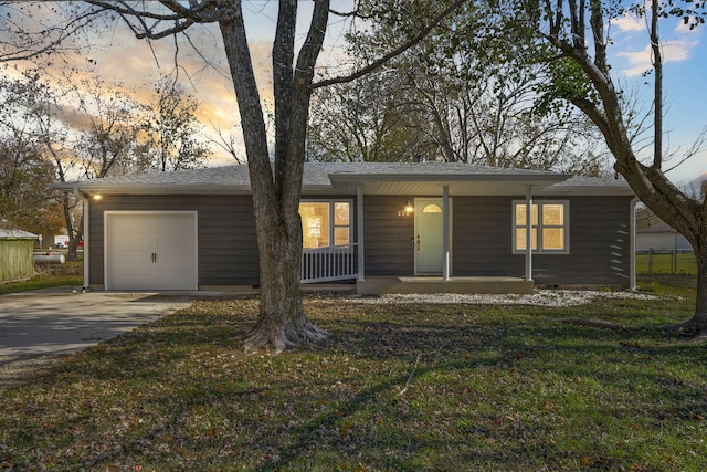 ranch-style home with a porch, a garage, and a yard