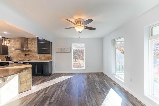 kitchen with tasteful backsplash, plenty of natural light, wall chimney exhaust hood, and dark hardwood / wood-style floors