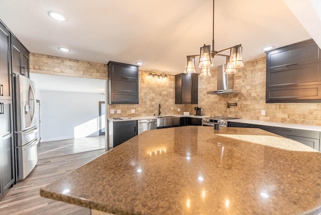 kitchen featuring decorative backsplash, appliances with stainless steel finishes, light stone counters, pendant lighting, and hardwood / wood-style flooring