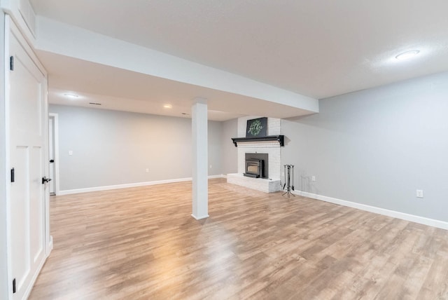 basement with a fireplace and light wood-type flooring