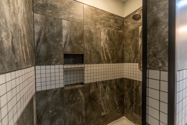 bathroom with tiled shower and tile walls