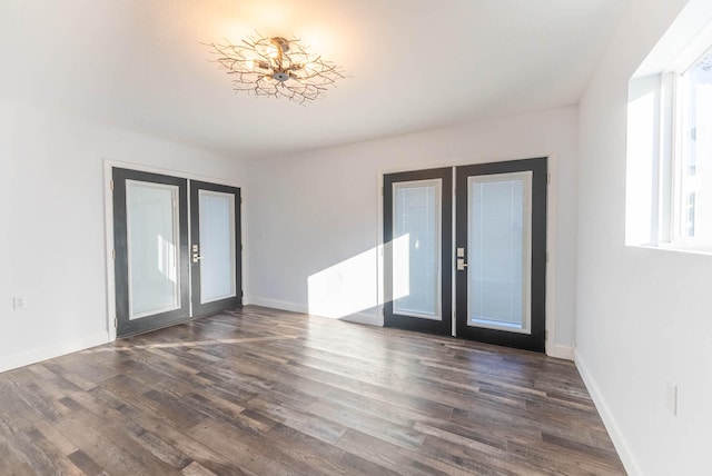 empty room with dark hardwood / wood-style flooring, french doors, and a notable chandelier