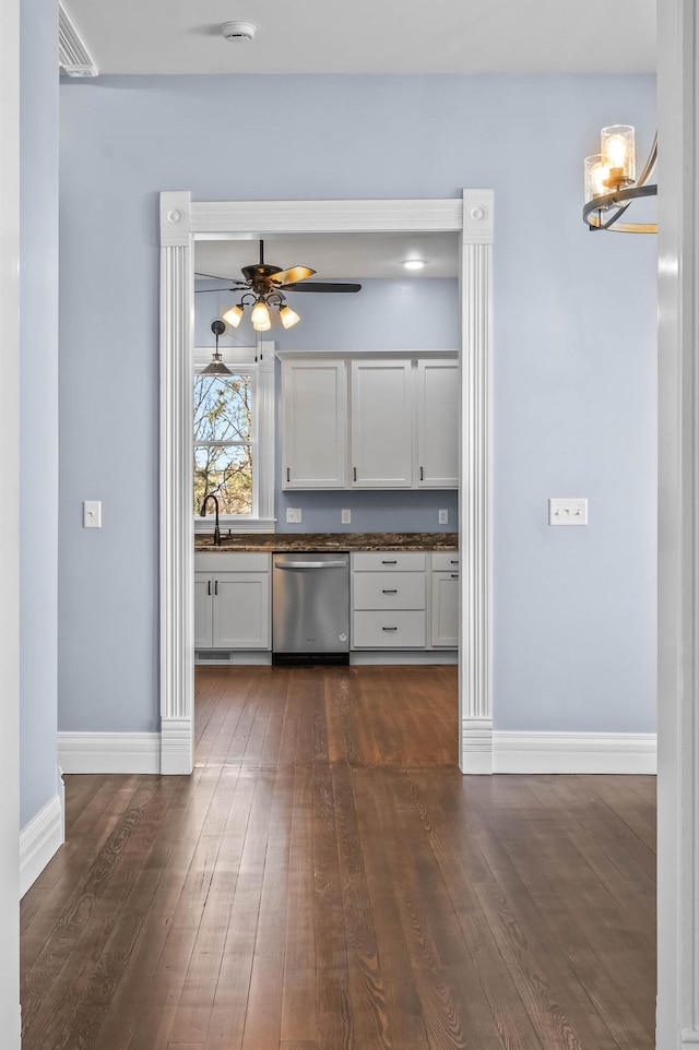 kitchen with dark hardwood / wood-style flooring, stainless steel dishwasher, ceiling fan with notable chandelier, sink, and white cabinetry