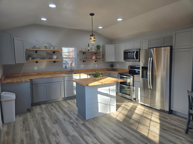 kitchen with wood counters, appliances with stainless steel finishes, light wood-type flooring, vaulted ceiling, and hanging light fixtures