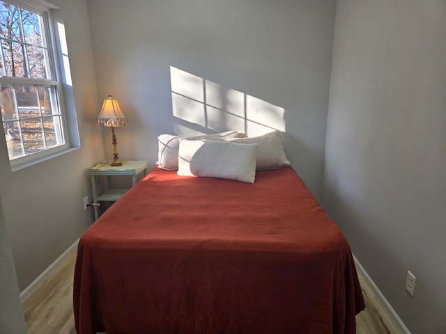 bedroom with light hardwood / wood-style floors and multiple windows