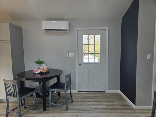 dining space featuring an AC wall unit and light hardwood / wood-style flooring