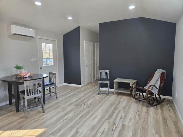 sitting room with a wall mounted air conditioner, light hardwood / wood-style flooring, and lofted ceiling