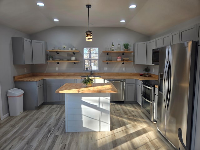 kitchen with decorative light fixtures, lofted ceiling, stainless steel appliances, and wooden counters