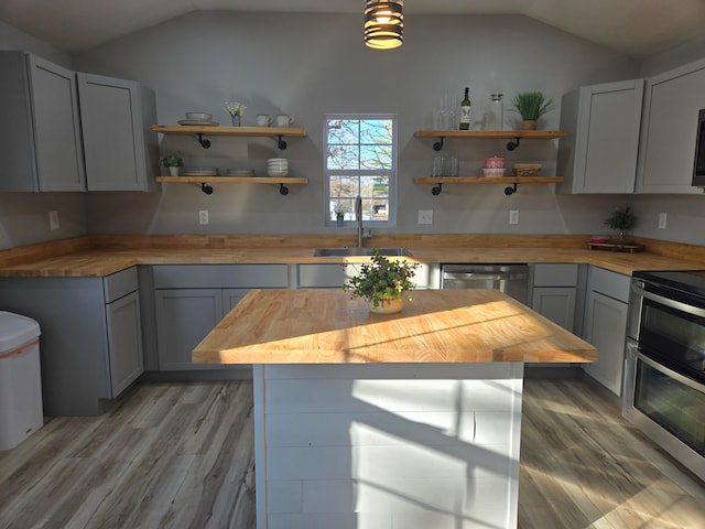 kitchen with gray cabinetry, wood counters, sink, light wood-type flooring, and stainless steel appliances