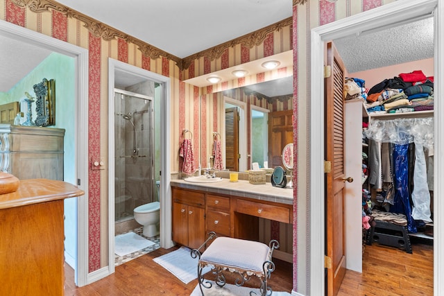 bathroom featuring vanity, hardwood / wood-style flooring, toilet, and a shower with shower door