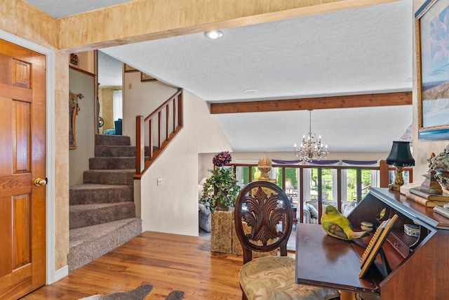 interior space with a textured ceiling, light wood-type flooring, lofted ceiling with beams, and a notable chandelier