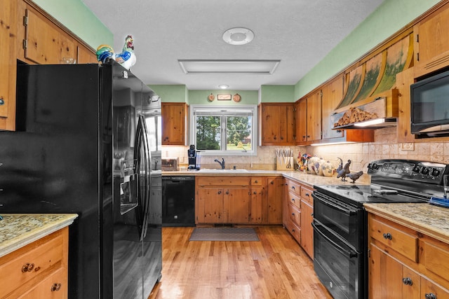 kitchen featuring decorative backsplash, a textured ceiling, sink, black appliances, and light hardwood / wood-style floors