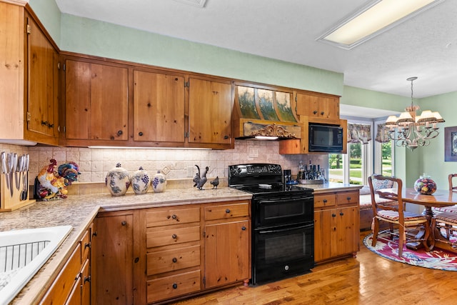 kitchen with black appliances, hanging light fixtures, tasteful backsplash, light hardwood / wood-style floors, and a chandelier