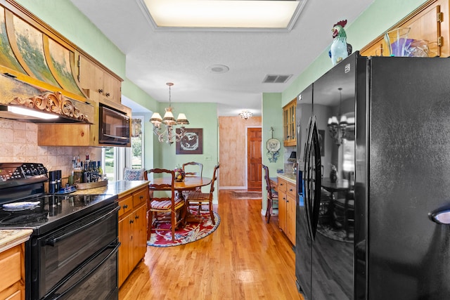 kitchen with pendant lighting, black appliances, decorative backsplash, light wood-type flooring, and a notable chandelier