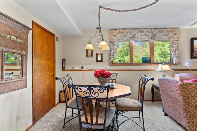 carpeted dining area with a notable chandelier and a textured ceiling