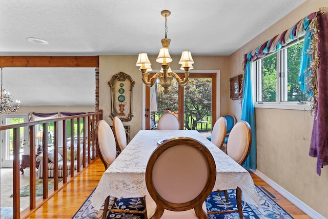 dining area with a notable chandelier, light hardwood / wood-style floors, and a textured ceiling