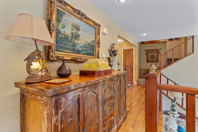 hall with light hardwood / wood-style flooring and a textured ceiling