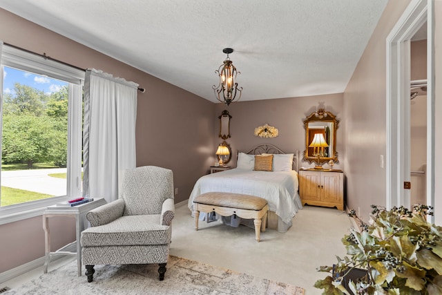 bedroom featuring carpet flooring, multiple windows, a textured ceiling, and a notable chandelier