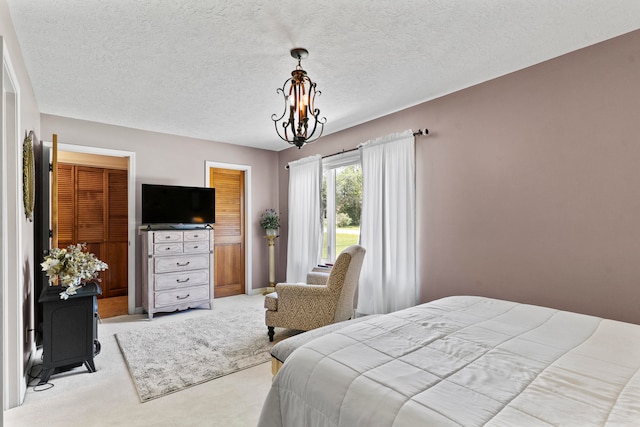 carpeted bedroom featuring a textured ceiling and a notable chandelier