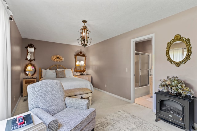 carpeted bedroom with ensuite bathroom, a textured ceiling, and an inviting chandelier