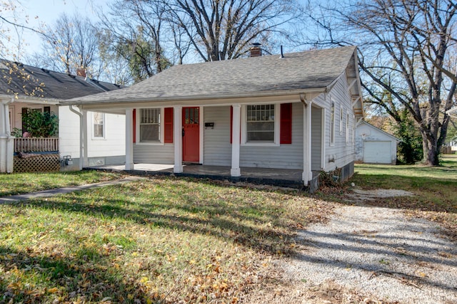 view of front of house featuring a porch, a garage, a front lawn, and an outdoor structure