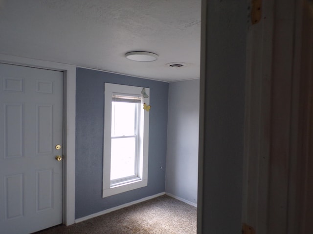 unfurnished room with a textured ceiling, carpet floors, and a healthy amount of sunlight