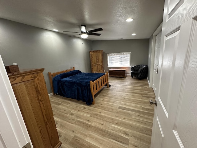 bedroom with ceiling fan, light hardwood / wood-style floors, and a textured ceiling