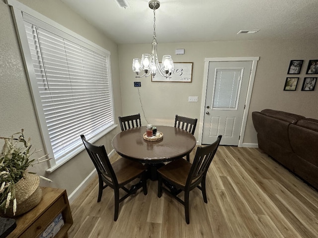 dining space with light hardwood / wood-style flooring and a notable chandelier