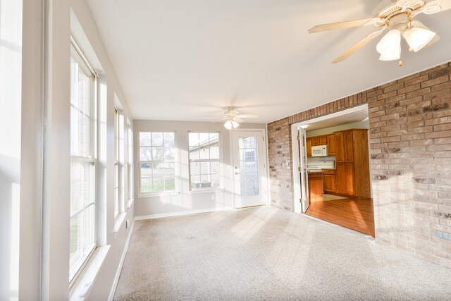 unfurnished sunroom with ceiling fan