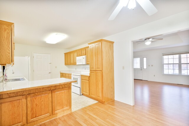 kitchen with ceiling fan, sink, kitchen peninsula, white appliances, and light wood-type flooring