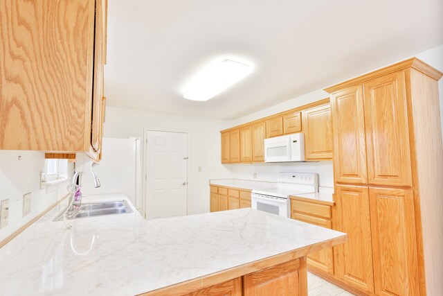 kitchen featuring kitchen peninsula, light brown cabinetry, white appliances, and sink