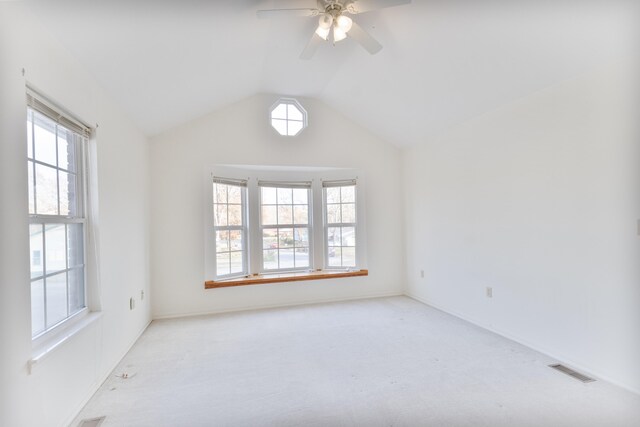 carpeted empty room featuring ceiling fan, plenty of natural light, and vaulted ceiling