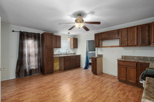 kitchen with sink, hanging light fixtures, crown molding, stove, and light wood-type flooring