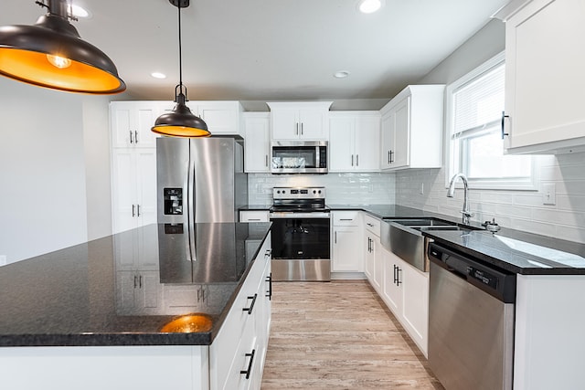 kitchen featuring white cabinets, decorative light fixtures, and appliances with stainless steel finishes