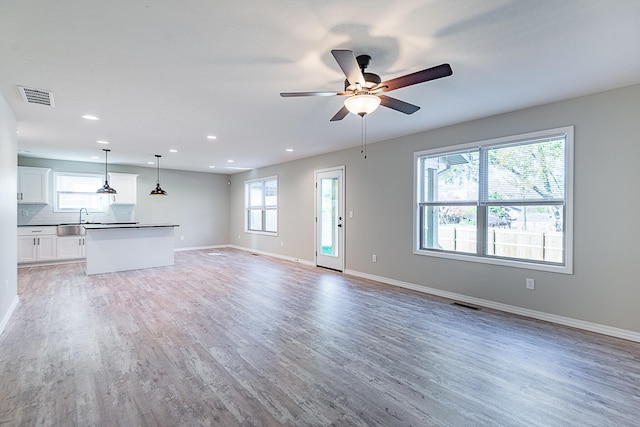 unfurnished living room featuring ceiling fan, wood-type flooring, and sink