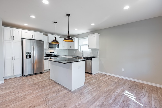 kitchen featuring white cabinets, appliances with stainless steel finishes, decorative light fixtures, and light hardwood / wood-style flooring