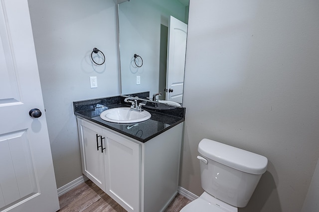 bathroom with toilet, vanity, and hardwood / wood-style flooring