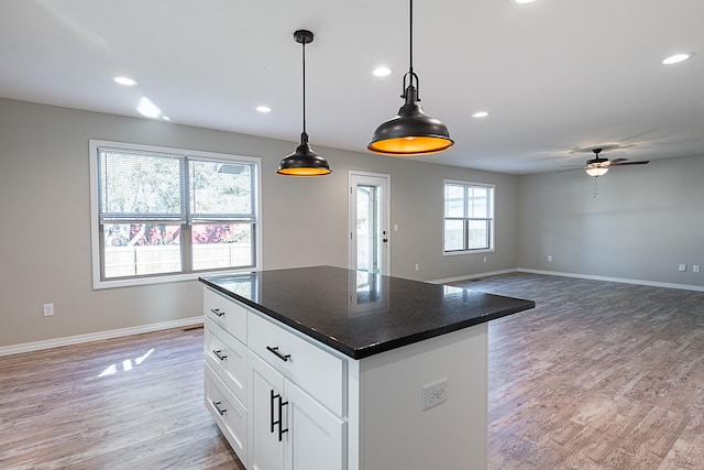 kitchen with white cabinets, decorative light fixtures, wood-type flooring, and a wealth of natural light