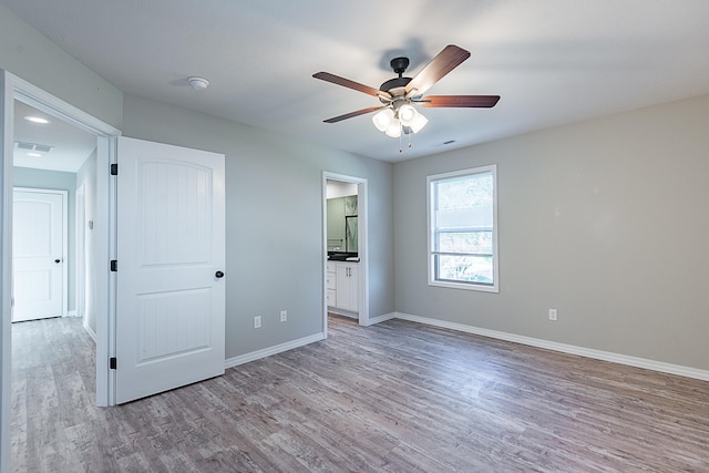 unfurnished bedroom featuring ceiling fan, light hardwood / wood-style floors, and connected bathroom