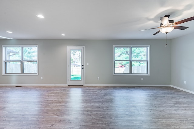 empty room with ceiling fan, plenty of natural light, and hardwood / wood-style flooring