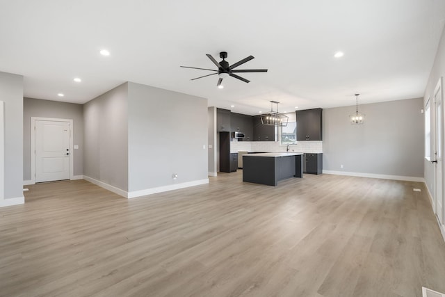 unfurnished living room featuring ceiling fan, sink, and light wood-type flooring