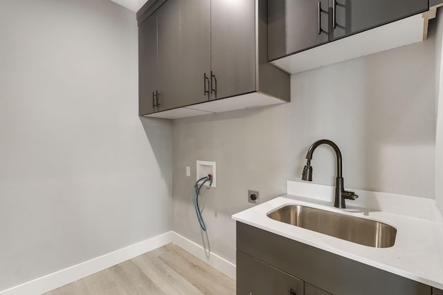 laundry room with electric dryer hookup, cabinets, sink, light hardwood / wood-style flooring, and washer hookup